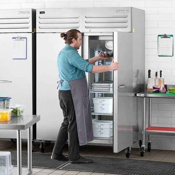 A man opening a Beverage-Air stainless steel reach-in freezer.