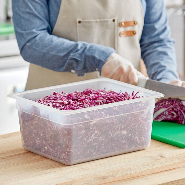 A person cutting red cabbage in a Vigor translucent plastic food pan.