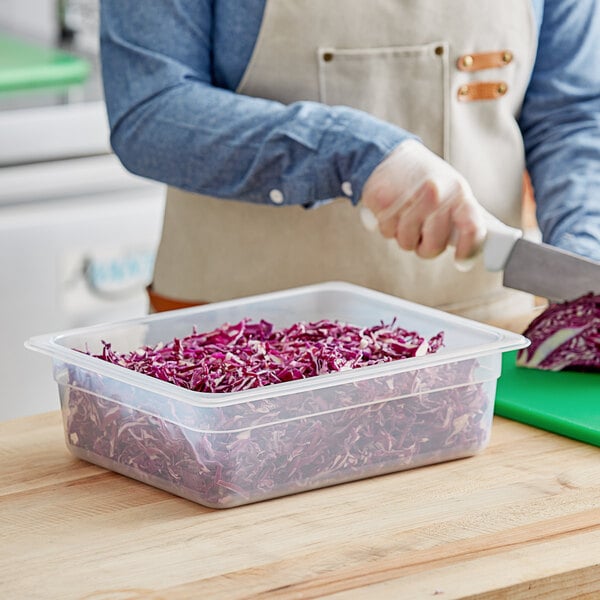 A person cutting red cabbage in a Vigor translucent plastic food pan.