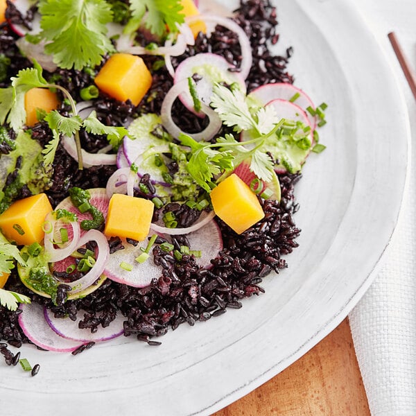 A plate of food with black rice and vegetables.