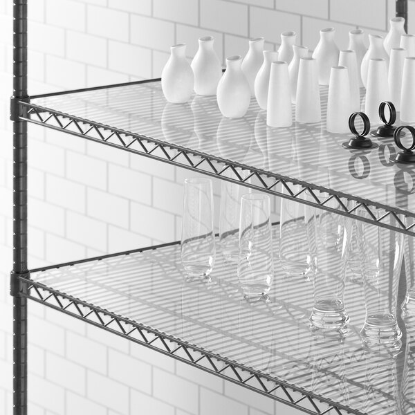 A Regency shelving unit with white vases and glasses on clear shelves.