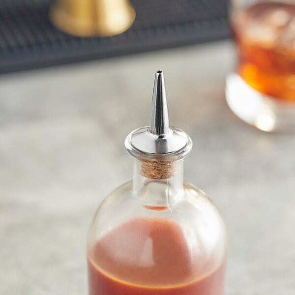 A Tablecraft stainless steel bottle dasher top on a bottle of liquid.