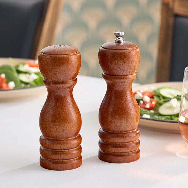 An American Metalcraft mahogany wood salt shaker and pepper mill set on a table.