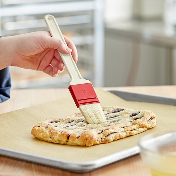 A person using a Choice natural bristle pastry brush to baste a pastry.