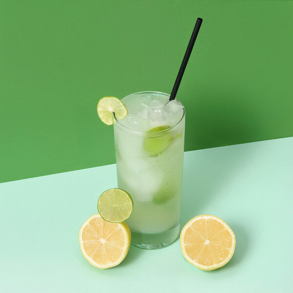 A glass of limeade with ice and a lime slice with a Greenprint Black Agave straw.