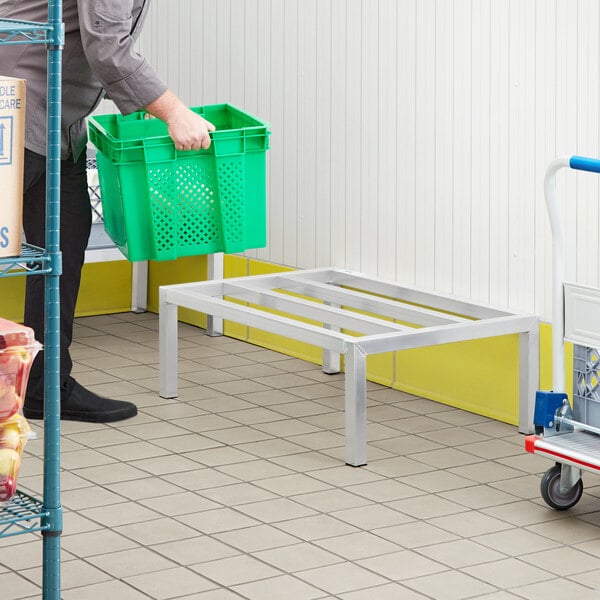 A man holding a Regency aluminum dunnage rack in a warehouse.