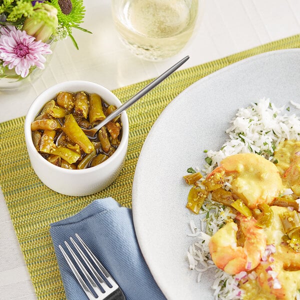 A plate of Indian food with a bowl of Ashoka Green Chilli Pickle and a fork.