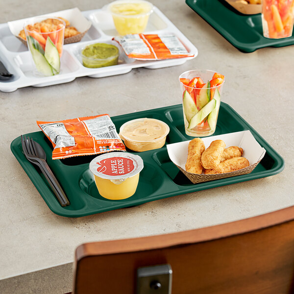 A left handed Choice heavy-duty melamine 6 compartment tray with food, a spoon, and a fork on a green surface.