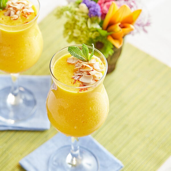 Two glasses of Ashoka Alphonso mango pulp on a table.