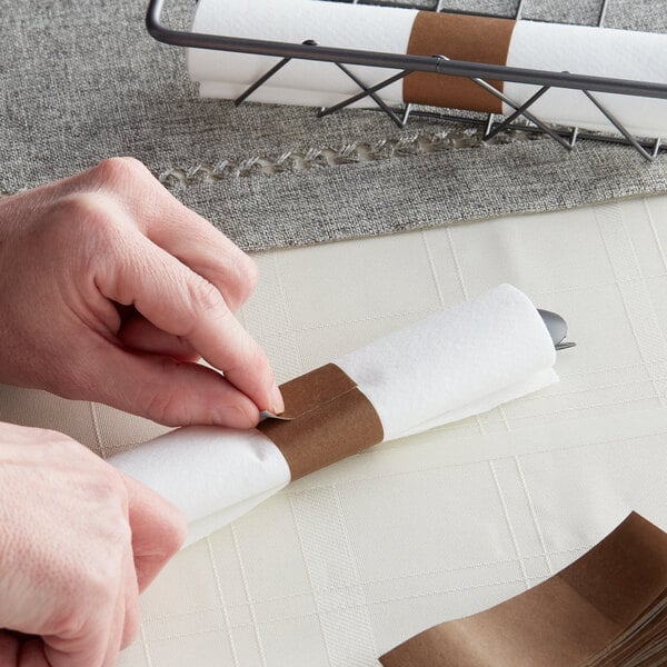 A person's hands using a knife to cut a piece of brown paper.