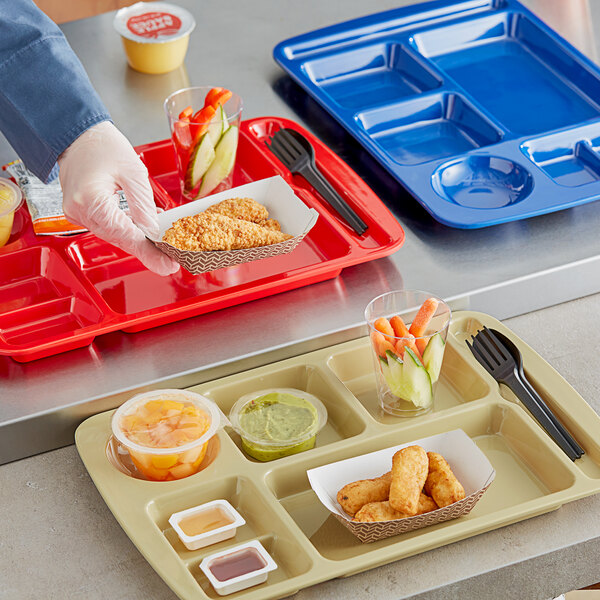 A person holding a tan Choice right handed compartment tray with food in it.