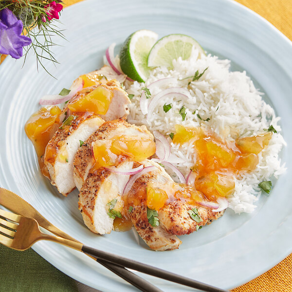 A plate of chicken with Ashoka Sweet Mango Chutney on a table.