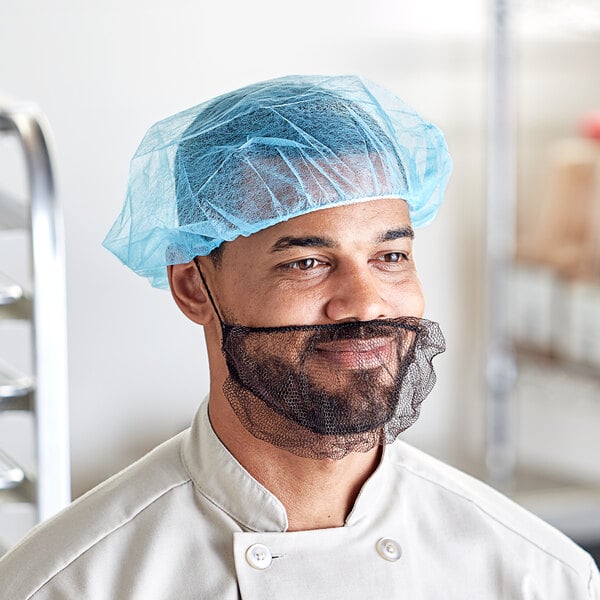 A man with a beard wearing a blue disposable polypropylene bouffant cap on his head.