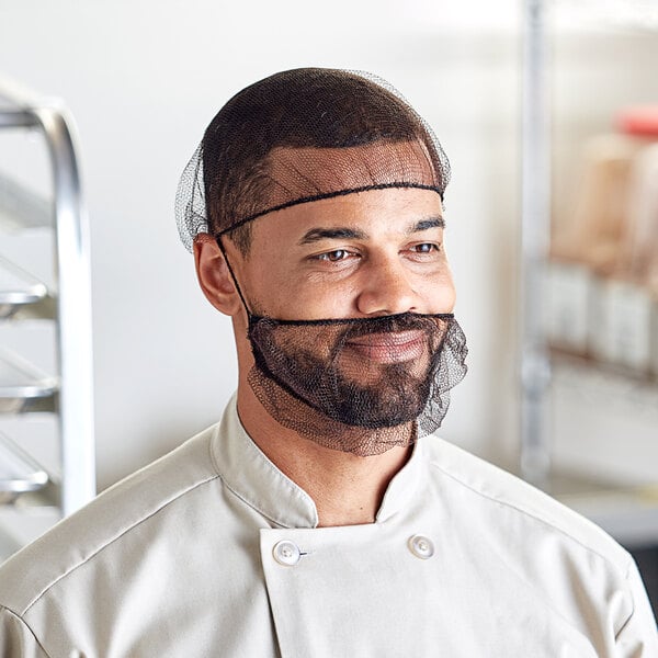 A man in a chef's uniform wearing a black hairnet over his head.