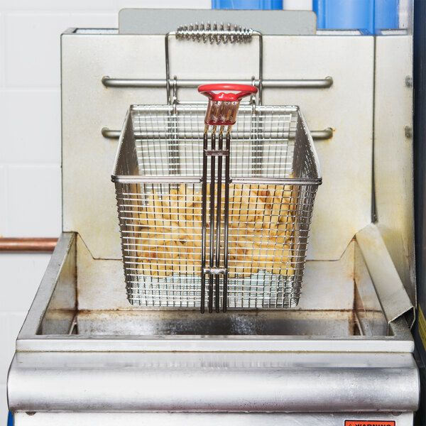 A Grindmaster-Cecilware fryer basket filled with fries in a deep fryer.