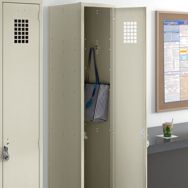 A beige metal locker from Regency Space Solutions with a blue and white striped bag inside.