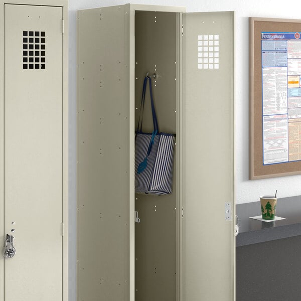 A beige metal locker with a blue and white striped bag inside.