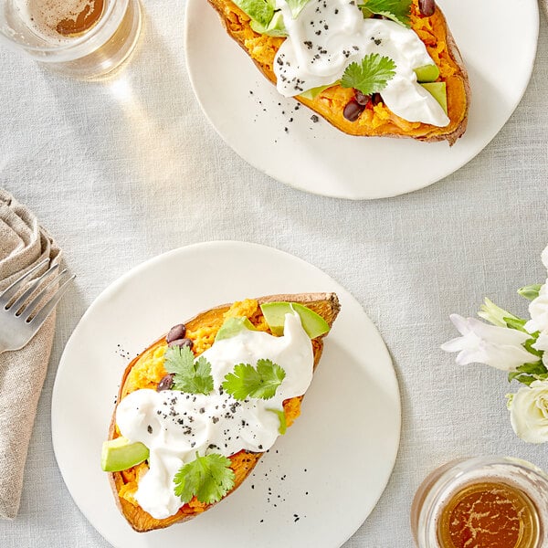 A plate with a sweet potato topped with Follow Your Heart Vegan Sour Cream and cilantro.