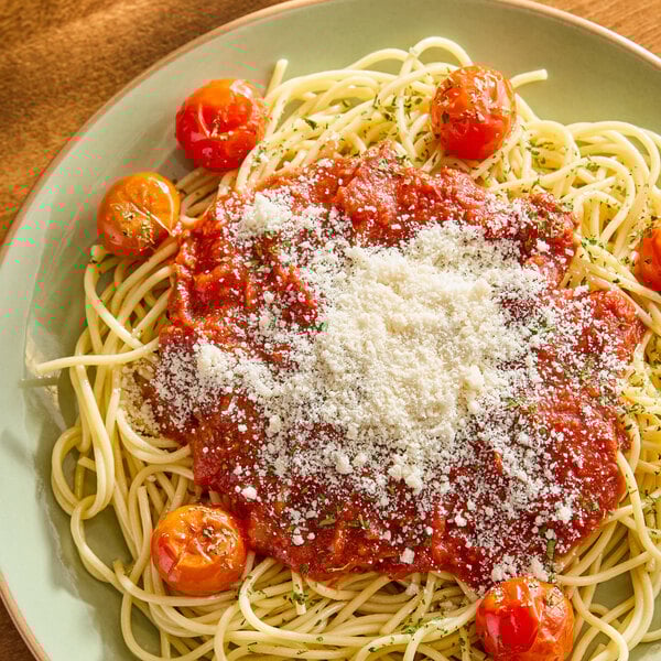 A plate of spaghetti topped with tomato sauce, cherry tomatoes, and a generous sprinkle of grated vegan parmesan cheese.