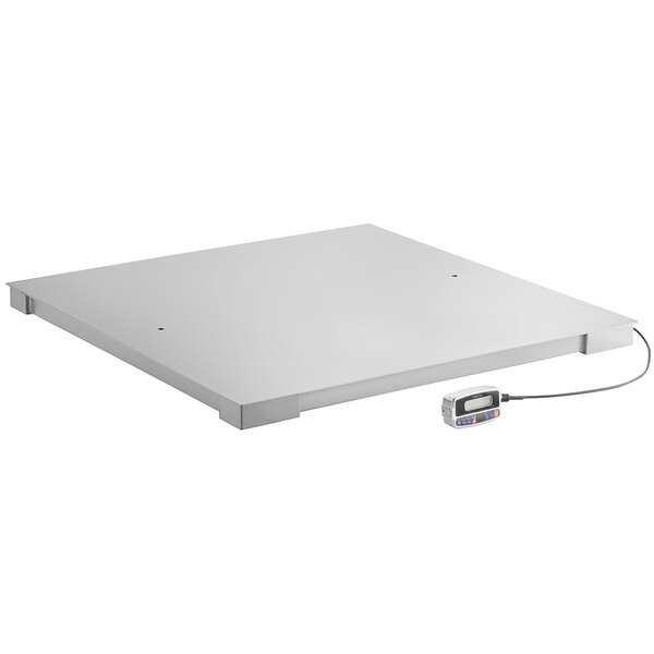 A white square Tor Rey industrial floor scale with a wire attached.