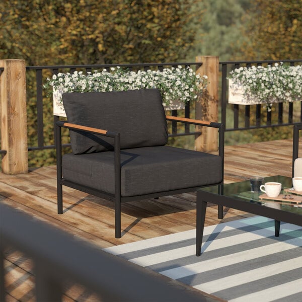 A black Flash Furniture patio chair with teak accents on an outdoor patio.