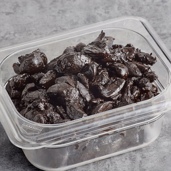 A plastic container with peeled black garlic bulbs inside.