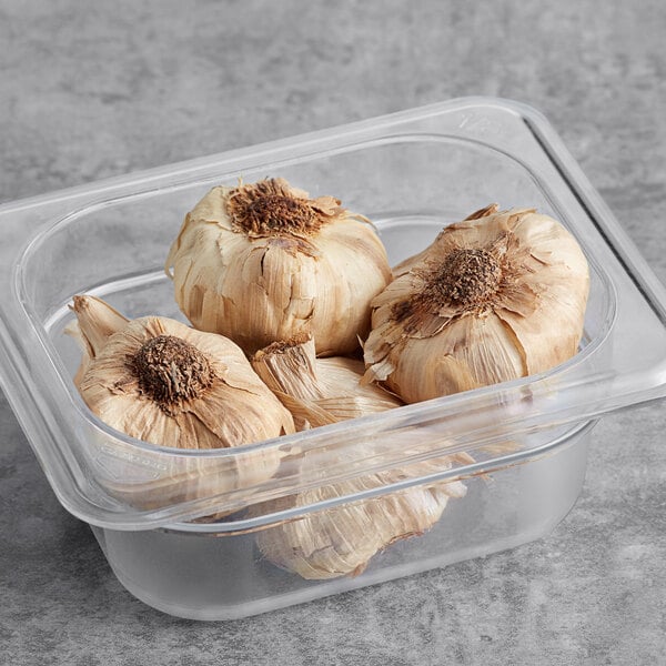 A plastic container of whole black garlic bulbs.