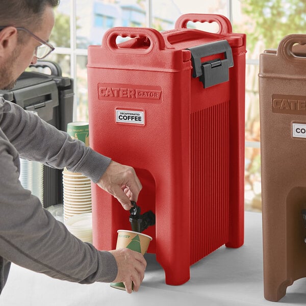 A man pouring coffee into a red CaterGator insulated beverage dispenser.