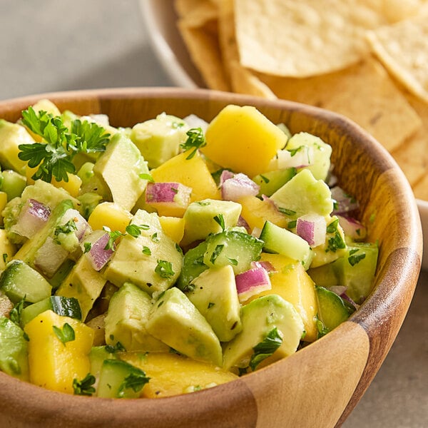 A bowl of avocado and mango salsa with tortilla chips.