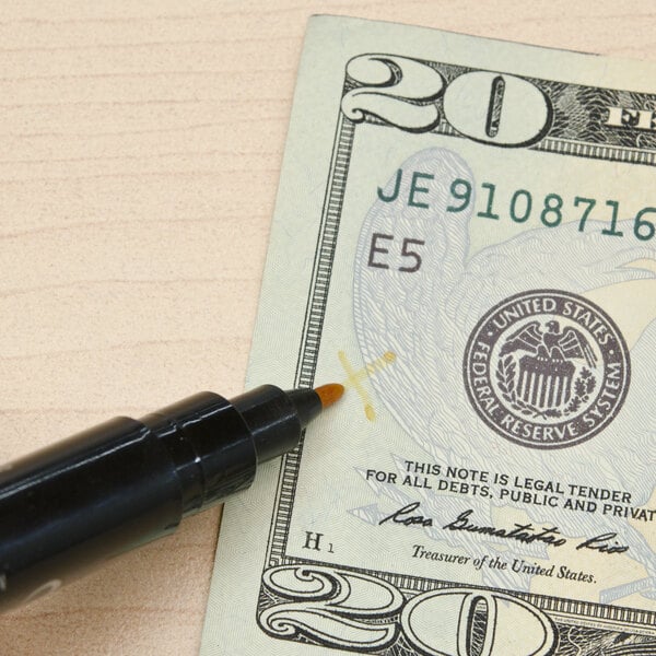 a counterfeit detector pen beside a $20 bill