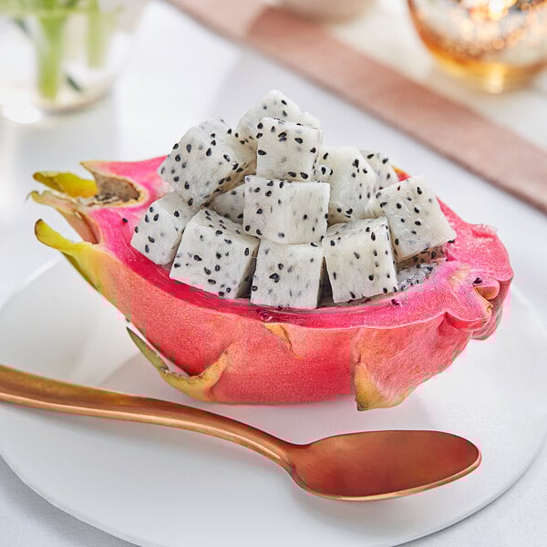 A half of a cut Fresh Pink Dragon Fruit with black seeds and a spoon.