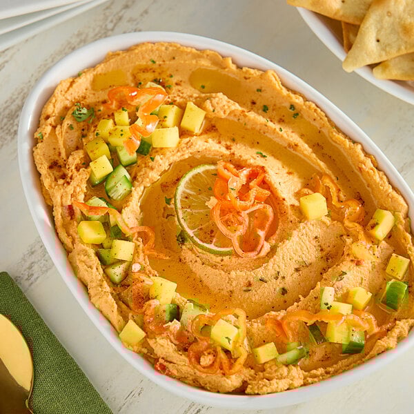 A bowl of food with a lime wedge and a bowl of Fresh Orange Habanero Peppers.