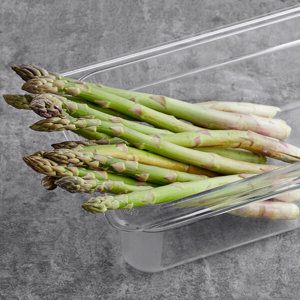 A glass container of fresh jumbo asparagus.