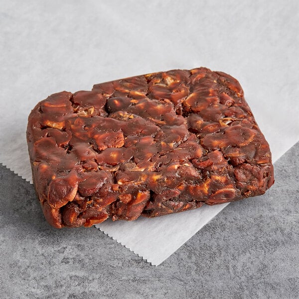 A brown rectangular block of seedless sour tamarind pulp on a white napkin.