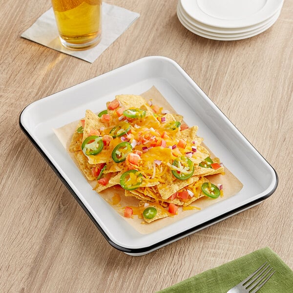 A Tablecraft black and cream white enamelware serving tray with nachos, cheese, and jalapenos on it.