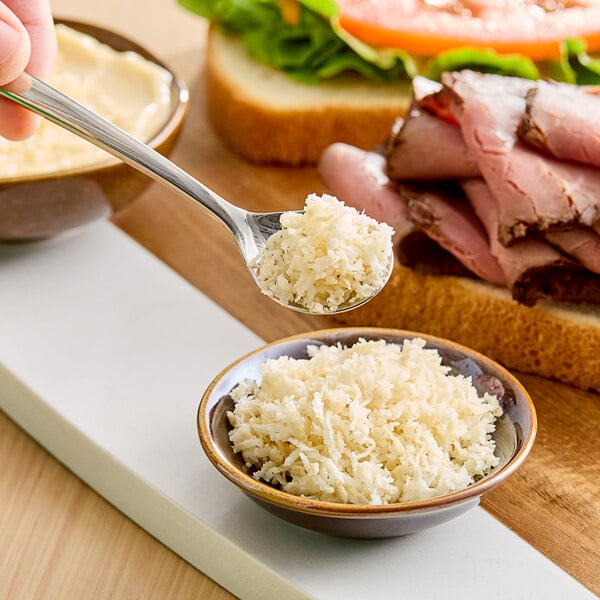 A hand holding a spoonful of fresh whole horseradish.