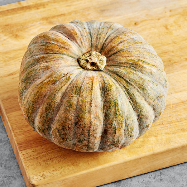 A Fresh Calabaza squash on a table sitting on a cutting board.