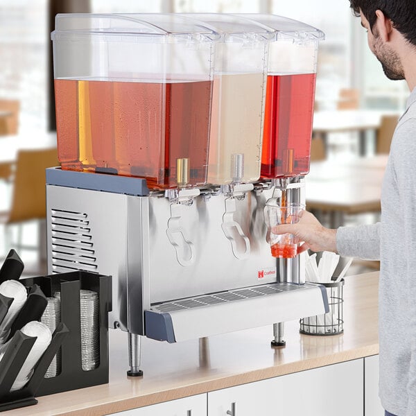 A man using a Crathco cold beverage dispenser to pour liquid into a glass.