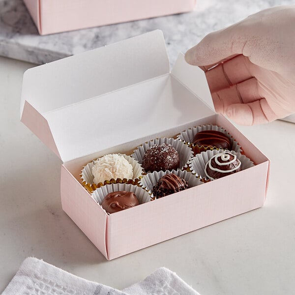 A hand holding a pink linen candy box.