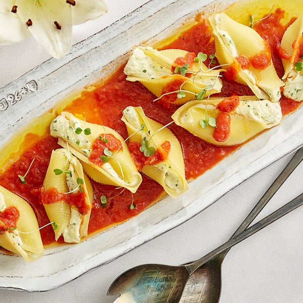 A plate of Barilla jumbo pasta shells with sauce and cheese.