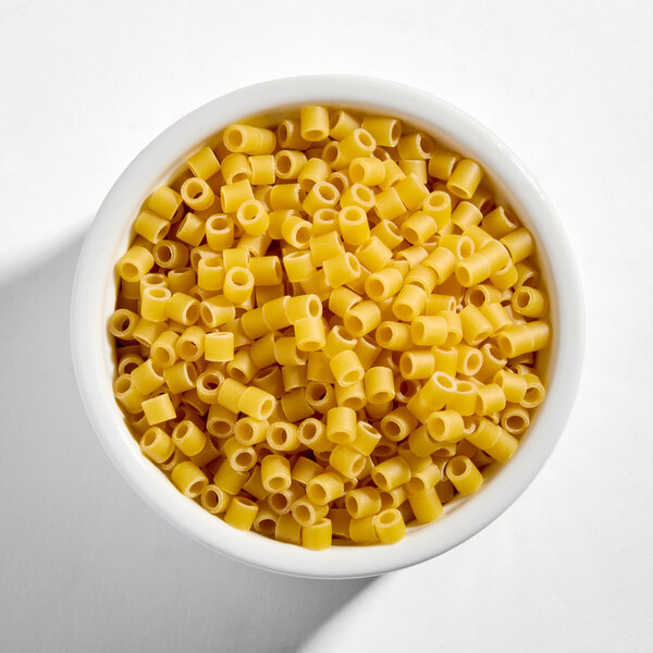 A white bowl filled with uncooked Barilla Ditalini pasta.