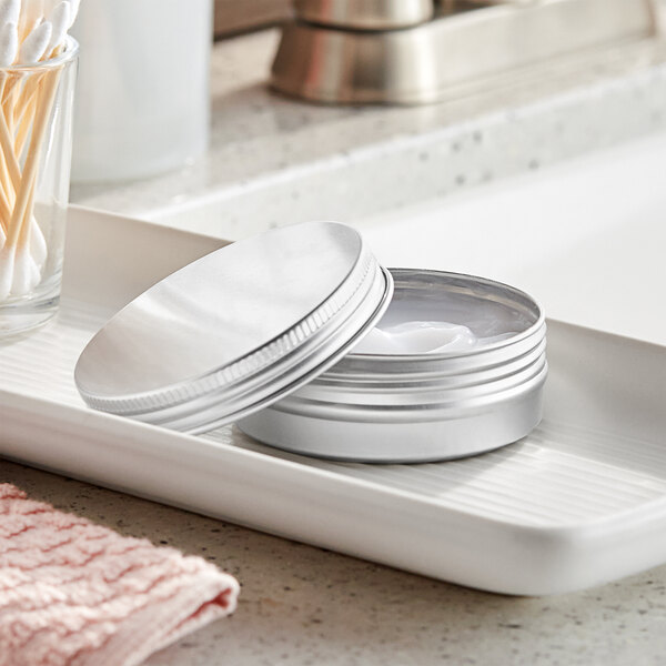 A silver metal tin with a ribbed screw top on a tray.