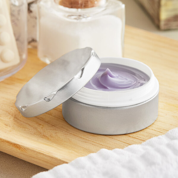 A silver tin of cream with a notched lid on a wood surface.