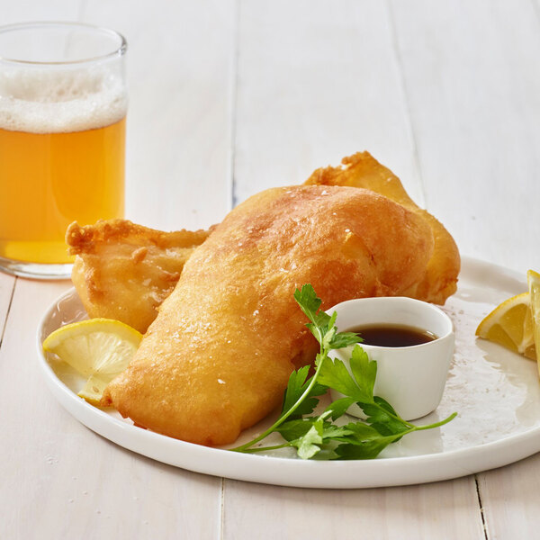 A plate of Golden Dipt beer-battered fried food with a lemon wedge and a glass of beer.