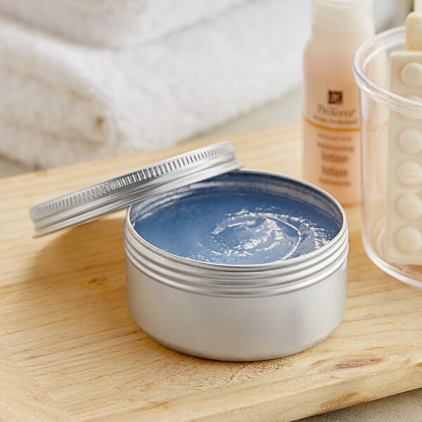 A silver tin of blue cream on a wood surface.