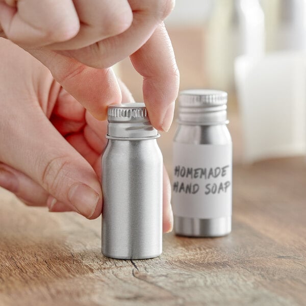 A person holding a silver aluminum bottle with a lid.