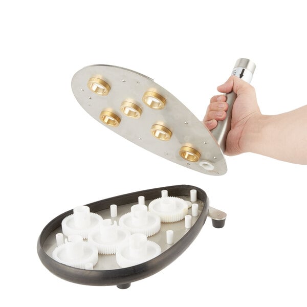 A hand holding a white plastic gear with bronze metal plates with holes.