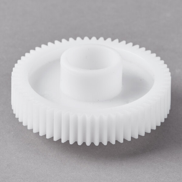 A white Galaxy brush drive gear with a hole on a gray surface.