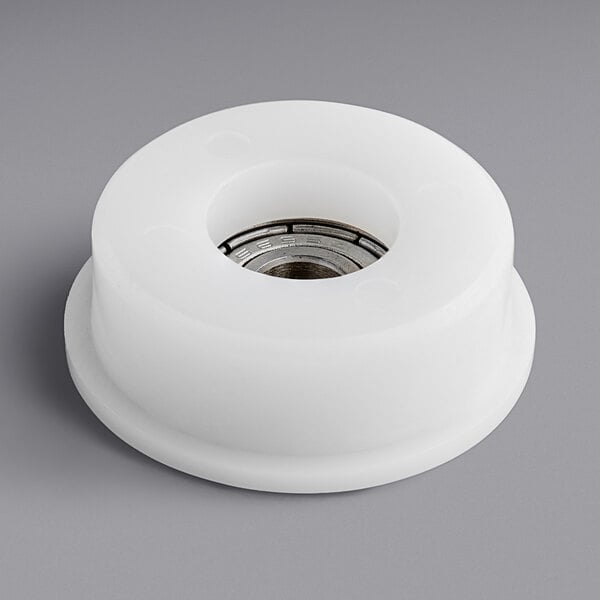 A white plastic wheel with a metal ring and a hole in it.