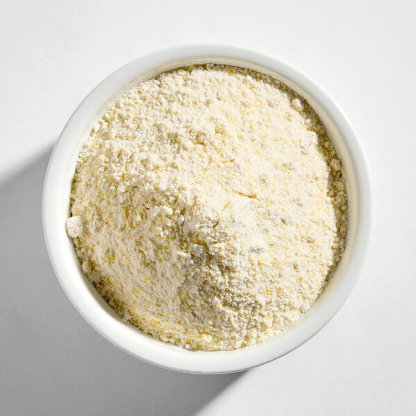 A white bowl filled with a yellowish, coarse hush puppy mix with onion.